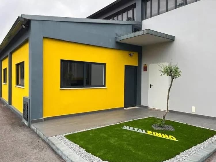 Fachada amarela e entrada das instalações da MetalPinho, com o nome da empresa no relvado