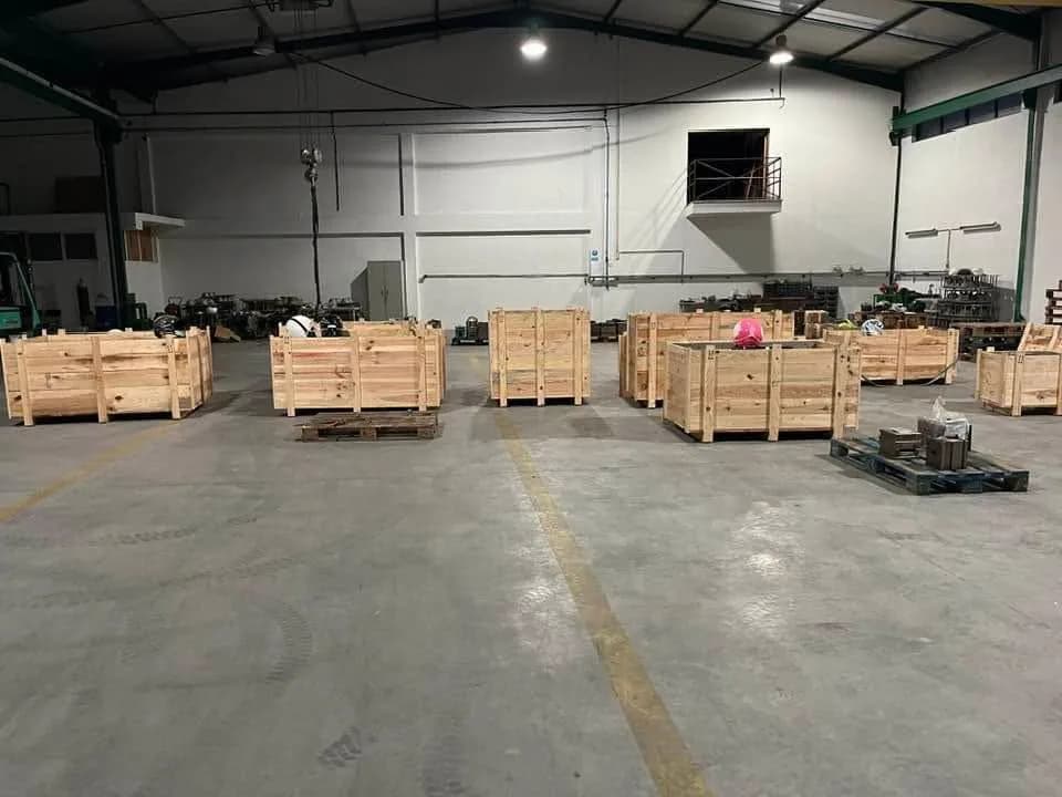 Fila de caixotes de madeira abertos, distribuídos pelo pavimento da nave