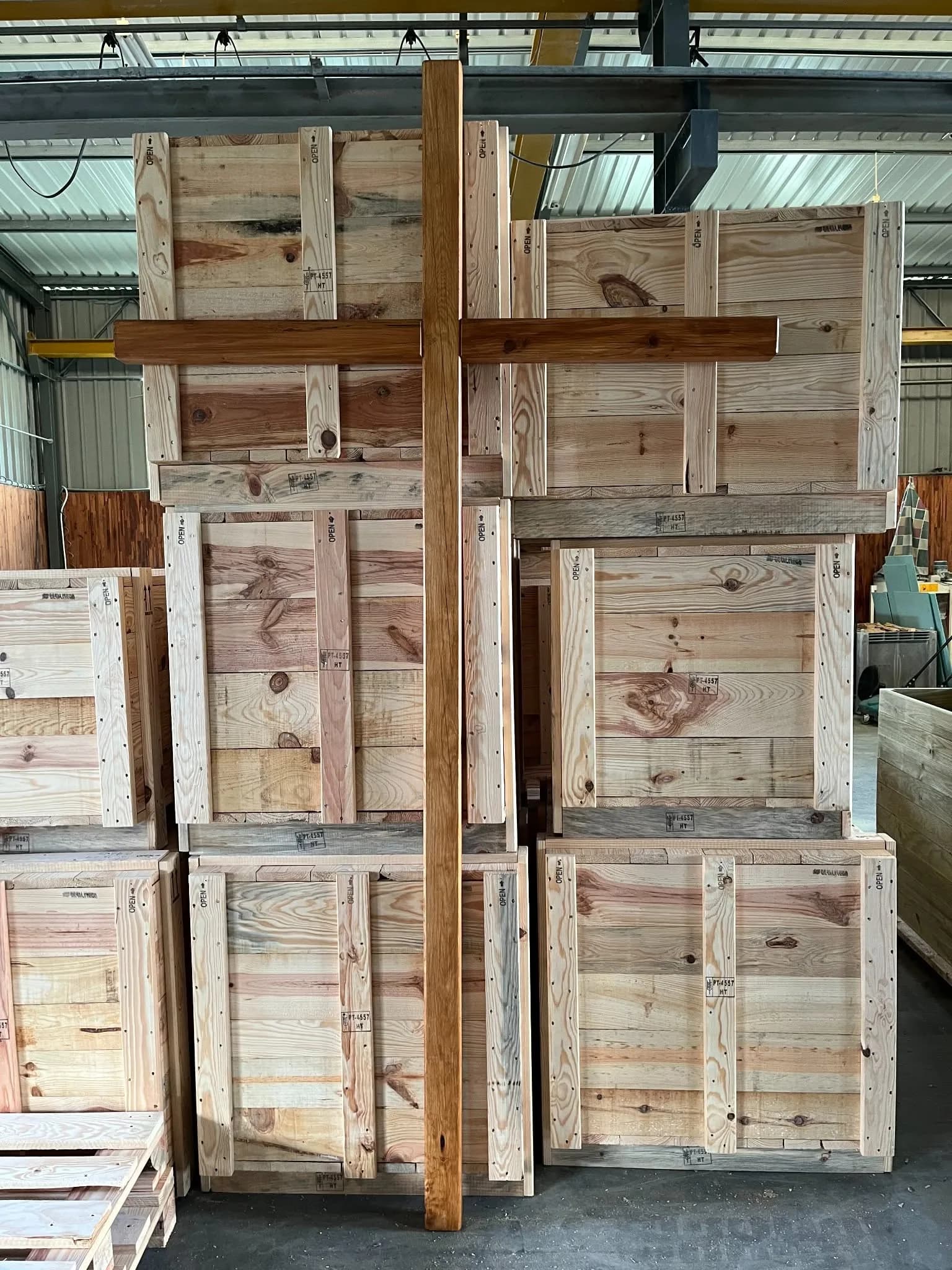 Painéis de caixote em pinho encostados em pilha na oficina, antes da montagem